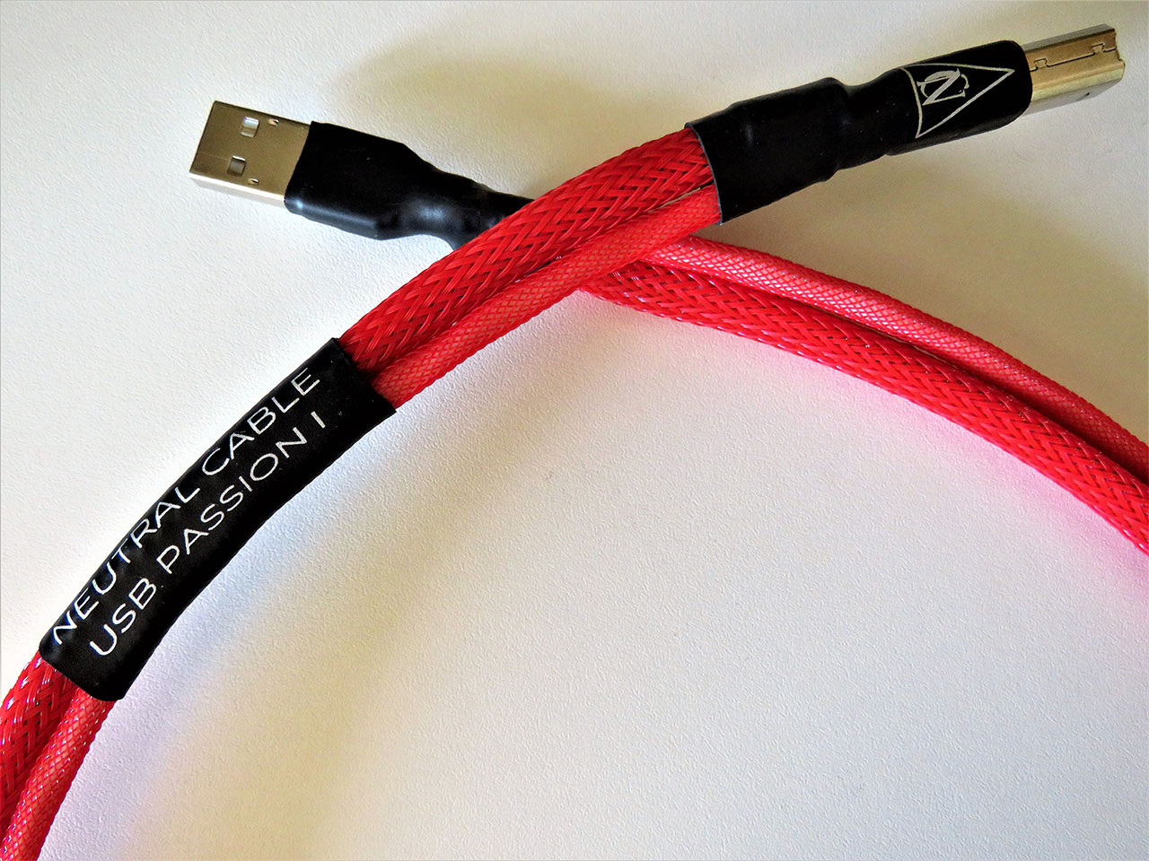 Cavo USB di alta qualità rosso intrecciato con connettori USB-A e micro USB, etichetta nero con testo “NEUTRAL CABLE USB PASSION”. Cavo USB di alta qualità rosso intrecciato con connettori USB-A e micro USB, etichetta nero con testo “NEUTRAL CABLE USB PASSION”.